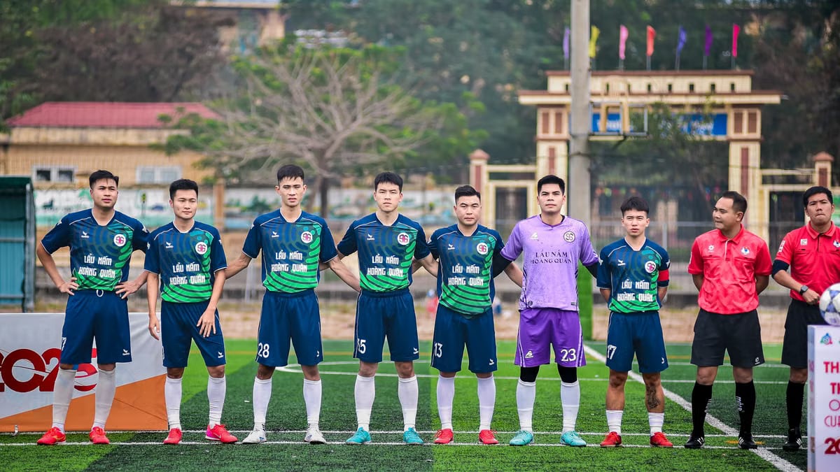 Soccer players and referees standing together on a field in Hà Nội, Vietnam.